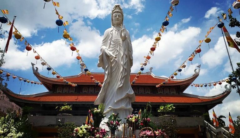 Grande statue de Bouddha blanc maigre devant une pagode au Vietnam, symbole de simplicité et de spiritualité. Les statues dans la philosophie du bouddhisme ont pour but de rappeler les enseignements du bouddha.