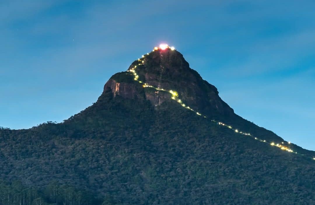 Vue nocturne du Pic d’Adam illuminé par la file de pèlerins montant vers le sommet, au cœur des montagnes du Sri Lanka.